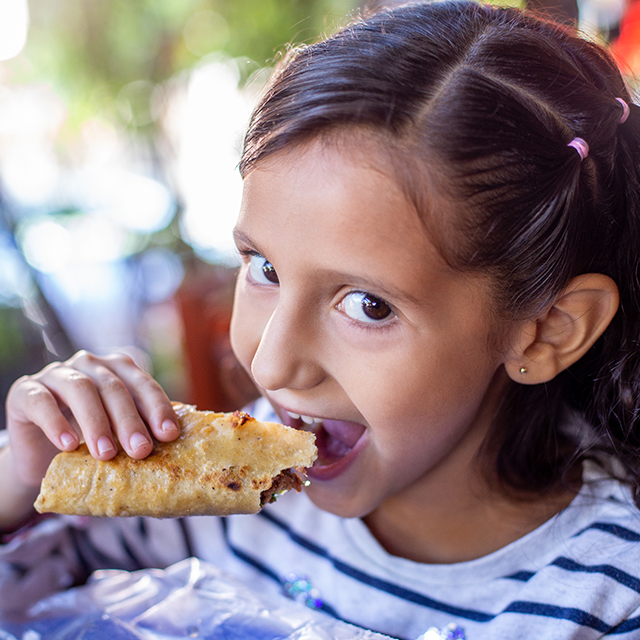 Niña disfrutando de un taco de birria